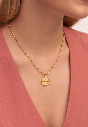 Collar de oro con un colgante redondo inscrito con "ABUELA" y piedras de acento coloridas, colgado de una cadena retorcida.