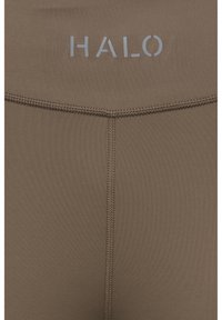 Zbliżenie brązowej tkaniny ze wzmocnionymi szwami i słowem „HALO” nadrukowanym na szaro w pobliżu górnego środka.