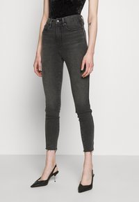 Höga grå denim skinny jeans med en blekt textur och rå fåll, kombinerat med svarta spetsiga slingback-häckar.