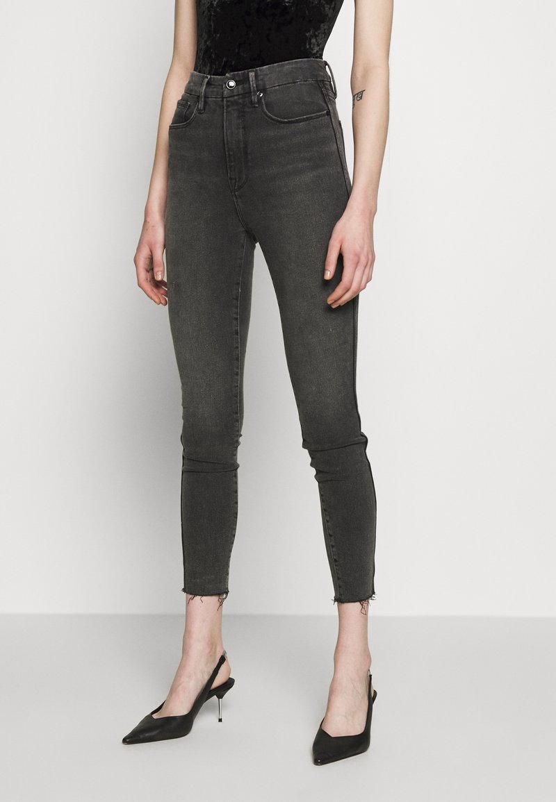 Höga grå denim skinny jeans med en blekt textur och rå fåll, kombinerat med svarta spetsiga slingback-häckar.