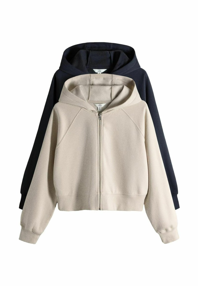 Zwei mittelgroße Kapuzen-Sweatshirts mit Reißverschluss, eines beige vorne und eines schwarz dahinter, auf weißem Hintergrund dargestellt.