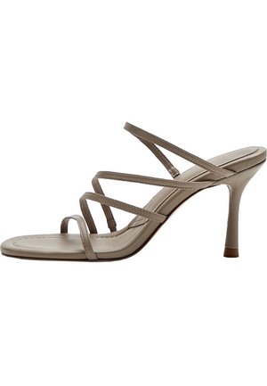 Sandale beige à talon haut avec fines brides croisées et bout ouvert sur un talon aiguille fin.