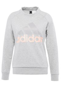 Felpa grigia realizzata in tessuto morbido, con maniche lunghe, scollo rotondo e un grande logo rosa adidas sulla parte anteriore.