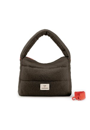 Borsa a mano in tessuto morbido marrone scuro con manico imbottito, una piccola etichetta rettangolare e una tracolla rossa staccabile accanto su sfondo bianco.