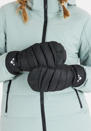 Svarta isolerade vantar med quiltad design, bärs av en person i en ljusblå jacka. Har logotyp på mudden och strukturerad yta.