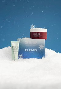 Pro-Collagen Bright Stars-settet inkluderer en rød rensebalsam og en grønn dagkrem, vist mot en snødekt bakgrunn med en blå eske.