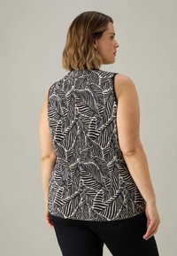 Top senza maniche con un motivo a foglie in nero e crema, in tessuto leggero, scollatura rotonda e texture liscia con una vestibilità comoda.