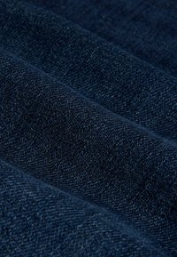 Ciemnoniebieska tkanina dżinsowa o miękkiej, gładkiej fakturze; charakteryzuje się subtelnym wzorem splotu i delikatnymi różnicami w kolorze.