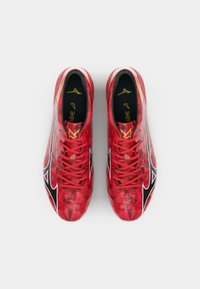 Rote Fußballschuhe mit einer strukturierten Oberfläche, die ein Diamantmuster aufweisen, schwarzen Akzenten und roten Schnürsenkeln. Das Markenlogo ist an der Seite sichtbar.