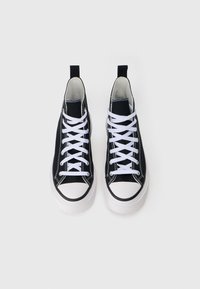 Sneakers neri in tela alta con suole e lacci bianchi, caratterizzati da cuciture a contrasto e una linguetta sul retro.