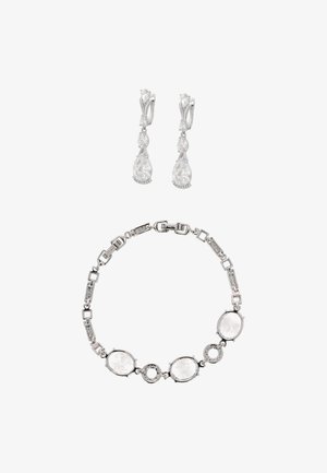 Silberschmuckset bestehend aus einem Armband mit ovalen und runden klaren Steinen sowie hängenden Ohrringen mit birnenförmigen klaren Steinen.