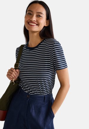 T-shirt rayé bleu marine et blanc avec un col rond, des manches courtes et une texture douce, associé à un pantalon taille haute bleu foncé.