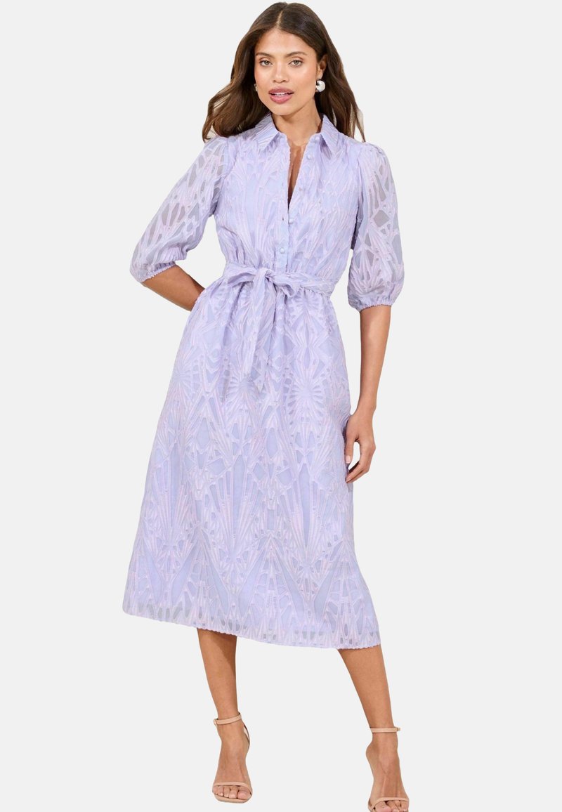 Hellblaues Kleid mit einer durchgehenden Knopfleiste, Bindegürtel und halbtransparenten, strukturierten Ärmeln. Es zeigt ein geometrisches Muster im gesamten Kleid.