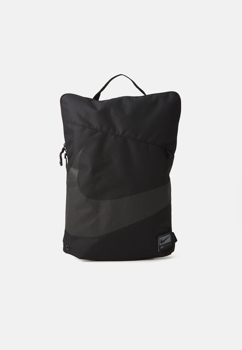 Svart vertikal ryggsekk med stor mørkegrå Nike swoosh, bærehåndtak på toppen, glidelåslomme på siden og liten frontetikett.
