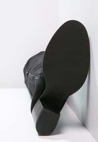 Bottines en suède noir avec un bout arrondi et un talon noir texturé. Comprend une fermeture éclair latérale et une semelle en caoutchouc avec des détails cannelés.