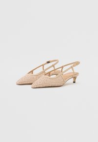 Escarpins slingback beiges à bout pointu avec petit talon kitten et motif géométrique texturé sur les orteils sur fond uni.