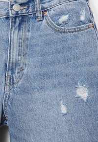 Hellblaue Denim-Shorts mit vorderen Taschen, Gürtelschlaufen, Knopfverschluss und drei ausgefransten, abgenutzten Stellen auf dem vorderen Stoff.