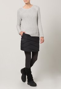 Šedý pletený svetr s dlouhými rukávy, doplněný černou prošívanou sukní, tmavými legínami a černými turistickými botami s texturovanými návleky na nohy.