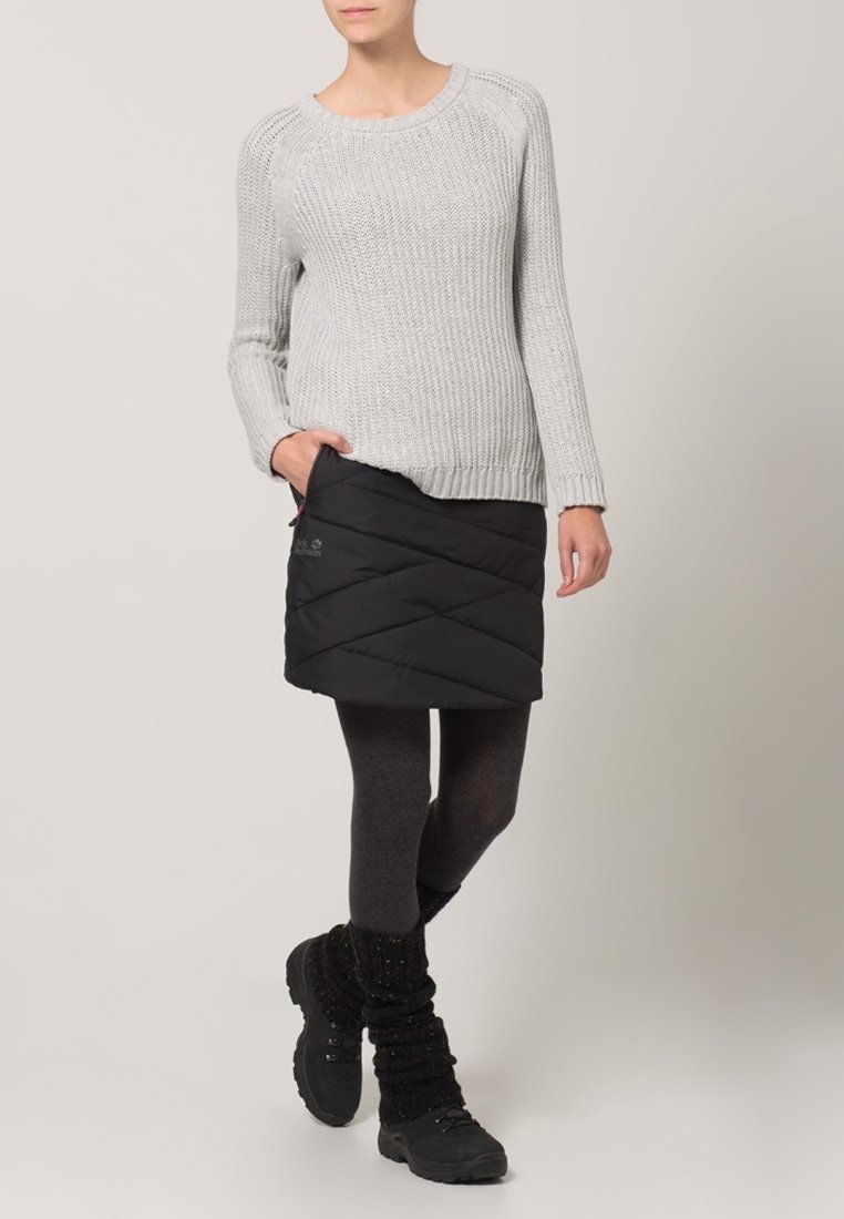 Šedý pletený svetr s dlouhými rukávy, doplněný černou prošívanou sukní, tmavými legínami a černými turistickými botami s texturovanými návleky na nohy.