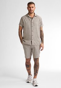 Gestreepte korte mouwen shirt en korte broek set in beige en bruin. Knopsluiting, casual pasvorm en bijpassend gestreept patroon.