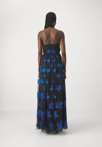 Schwarzes Maxikleid mit blauer Blumenstickerei, trägerloses Design, fließende Textur und Krawatte im mittleren Rückenbereich.