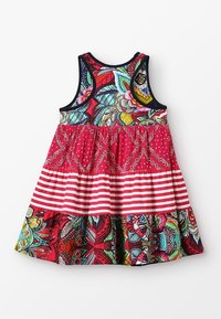 Kolorowa sukienka bez rękawów z kwiatowym wzorem na górze, czerwonym wzorzystym pasem w talii i paskowanym dołem. Żywe kolory i materiały.