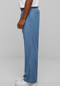 Lyseblå denimbukser med afslappet pasform, elastisk talje og sidelommer. Afsluttet med lige ben og subtile syningdetaljer.