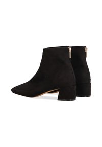 Botines de ante negros con punta afilada, pequeño tacón grueso y detalles de cremallera dorada en la parte posterior para un uso fácil.