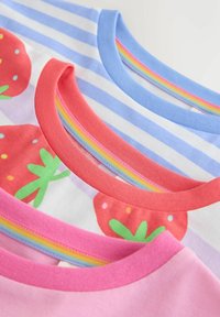 Tres camisetas infantiles dobladas con cuellos redondos; una rosa, una blanca con fresas rojas y una de rayas azules y blancas.