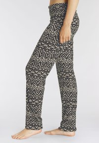 Geprinte leggings van zwart en beige stof, met een gestapelde tailleband en geometrische ontwerpen, nauwsluitend over het hele been.
