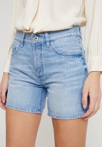 Pantalones cortos de denim en azul claro con un corte clásico, diseño de cinco bolsillos y cierre con botón de metal. Tejido suave con ligeros detalles de desgaste.