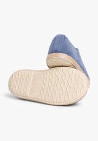Scarpe slip-on in suede blu con suola texturizzata, caratterizzate da un bordo in juta intrecciata lungo il contorno e un design con punta arrotondata liscia.