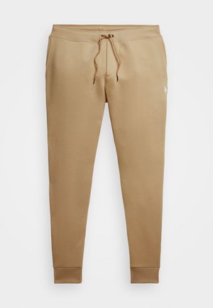 Tan sweatpants lavet af blødt stof, med snøre i taljen, ribbede manchetter og et lille logo på den nederste del af benet.