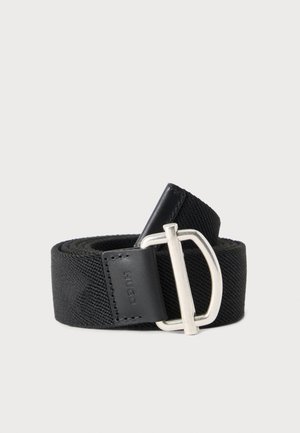 Ceinture en tissu tissé noir roulée avec une boucle métallique argentée en forme de D et une boucle en cuir noire avec le nom de la marque "HUGO" embossé.