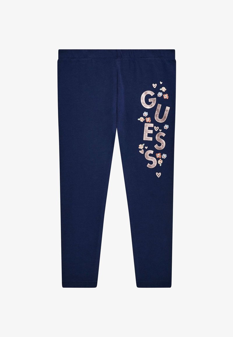Leggings azul marino con cinturilla elástica que presentan un logotipo texturizado de "GUESS" y acentos florales en rosa, azul y blanco en la pierna izquierda.