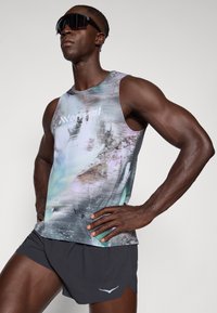 Tailliertes, ärmelloses Tanktop mit einem bunten, abstrakten Muster; kombiniert mit dunklen, leichten Shorts mit asymmetrischem Saum und dezentem Logo.