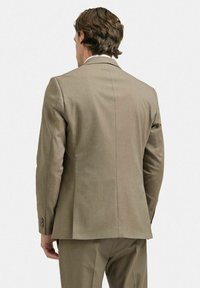 Beige kostymjacka med en slät textur, enkel vent, och tre knappar på varje ärm. Skräddarsydd passform, visad från baksidan.