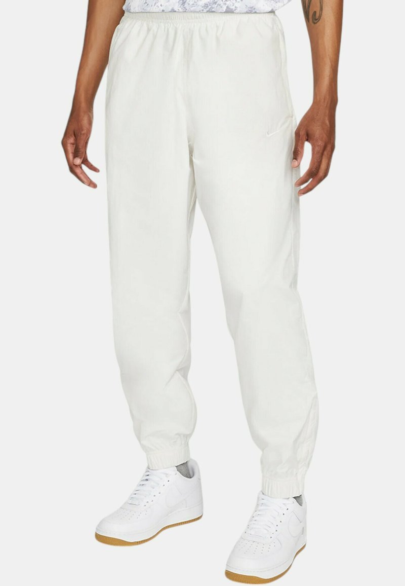 Vita, lätta joggarbyxor med elastisk midja, muddade anklar och en liten Nike-logga på vänster sida.