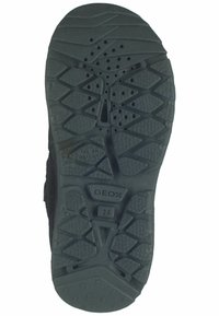 Suela de zapato de goma negra con una superficie texturizada que presenta un patrón de relieve geométrico, orificios de ventilación y un logo en relieve. Talla 28.