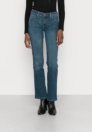 Jeans de denim azul con cintura ajustada, piernas acampanadas y un acabado ligeramente deslavado. Cuenta con cinco bolsillos y un cierre de botón de marca.