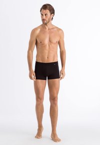 Men's black boxer briefs made of smooth fabric, featuring an elastic waistband, form-fitting design, and short leg length.
