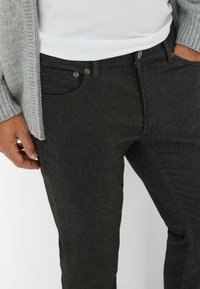 Mørkegrå denimjeans med et klassisk femlomme-design, subtil tekstur og metalknap hardware i taljen.