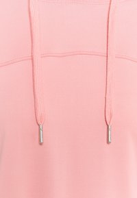 Sweat à capuche rose avec une texture lisse, doté d'une poche kangourou et de cordons avec des embouts en métal argenté. Design simple, sans motifs.