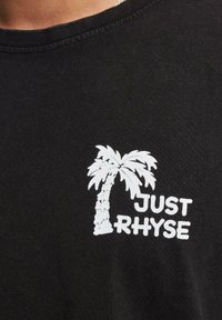 Melnas kokvilnas T-krekls ar balta palmu koka grafiku un uzrakstu "JUST RHYSE", apaļa izgriezne un īsas piedurknes.