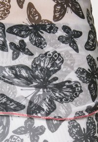 Padrão de borboletas pretas e cinzentas em um tecido branco e leve, com uma bainha com costura vermelha e uma superfície ligeiramente texturizada.