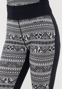 Black and white patterned leggings with a textured waistband. The fabric features geometric designs and animal motifs on a light background.