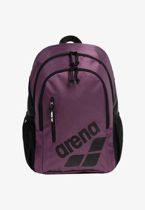 Lila Rucksack mit schwarzen Akzenten, gefertigt aus robustem Stoff, verfügt über verstellbare Träger, eine vordere Reißverschlusstasche und markantes schwarzes Branding.