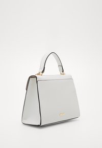 Strukturovaná bílá kabelka s hladkým povrchem, černými akcenty na okrajích, horním držadlem a zlatou logo destičkou na přední straně.