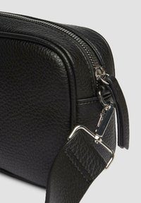 Schwarze Lederhandtasche mit strukturiertem Finish, silbernem Reißverschluss und Beschlägen. Verfügt über einen verstellbaren Tragegurt und eine klare, rechteckige Form.