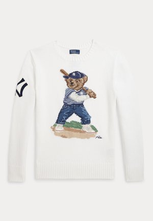 Biely pletený sveter s vyšívaným medvedíkom v baseballovom oblečení držiacim pálku a námorníckym logom na ľavom rukáve.